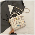 Detail view of white graffiti bucket bag with colorful patterns and golden metal hardware - White Large