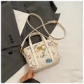 Close-up of white canvas bucket bag with colorful graffiti prints and gold hardware detail - White Small