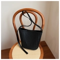 Détail du sac seau tissé noir montrant la texture Intrecciato sur une chaise en bois - Noir
