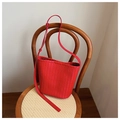 Vue détaillée du sac seau tressé rouge montrant la texture Intrecciato sur une chaise - Rouge