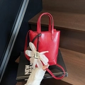 Sac seau rouge vif avec breloque marguerite et élégant ruban noir sur la poignée - Rouge