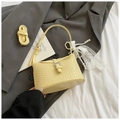Détail du sac seau tissé jaune avec boucle argentée et bandoulière réglable pratique - Jaune avec pendentif