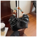 Detail of black pleated bucket bag with colorful beaded handle on wooden stairs - Black