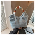 Dettaglio della borsa a secchiello in denim con borchie e manico in perle colorate - Blu