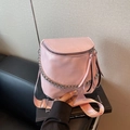 Schicke rosa Satteltasche mit Silberkette und breitem Nylongurt auf einem Sofa - Rosa