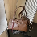 Brown faux leather tote bag with decorative buckle and woven pendant on a mirror surface - Brown (With Pendant)