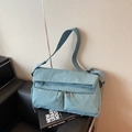 Light blue nylon crossbody messenger bag with double zipper pockets on black leather seat - Blue
