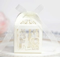 Macro shot of ivory laser-cut wedding favor box with ribbon and heart LOVE pattern - Ivory