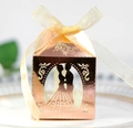 Close-up of rose gold hollow candy box with laser-cut bride and groom silhouette and ribbon - Reflective Rose Gold