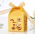Makroaufnahme einer gelben lasergeschnittenen Geschenkbox mit Kinderwagenmotiv - Gold