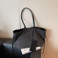 Minimalist black tote bag with matching pouch on a sleek leather sofa setting - Black