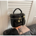 Detail of black quilted box bag with gold metal handle and heart charm pendant - Black