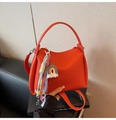 Détail d'un sac seau en cuir orange avec breloques décoratives et bandoulière de transport - Avec Pendentif / Orange