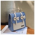 Primer plano de una mochila de mezclilla con ribetes de cuero y lazos decorativos - Azul claro
