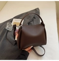 Détail du sac seau en cuir marron foncé avec un pendentif pompon tissé coloré - Avec Pendentif / Marron