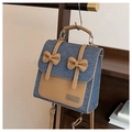 Detalle de mochila de tela vaquera azul y cuero marrón con lazos y logo de metal - Azul oscuro