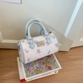 Mini-Boston-Tasche mit Bärenprint und blauen Riemen auf einem Stapel Bücher - Blau
