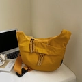 Close-up of yellow nylon crescent bag with woven zipper pulls on a white desktop - Large / Yellow