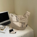 Detail of beige nylon dumpling bag featuring woven rope zipper and wide shoulder strap - Rice White Small