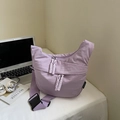 Close-up of lilac crescent crossbody bag with woven zipper pull and woven brand label - Lilac Small