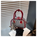 Detailed close-up of a blue denim mini Boston bag with red leather trim and star pendant - With Pendant / Red