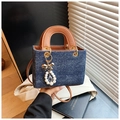 Close-up of denim Lady Dior style handbag with pearl bow charm and gold hardware - With Charm / Royal Blue