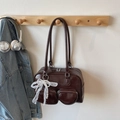 Dark brown glossy bowling bag with lace bow and pearl charm on a wooden hook - Coffee