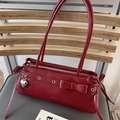 Dettaglio borsa baguette in pelle lucida rossa con ciondolo a cuore e fiocco decorativo - Rosso