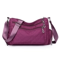 Detail view of purple quilted nylon crossbody bag featuring multi-pocket zipper design - Fuschia