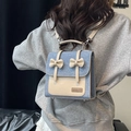 Sac à dos en denim bleu et cuir beige avec nœuds décoratifs porté par un mannequin - Bleu clair