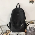 Minimalist black nylon backpack with a white brand label for students in a campus setting - Black
