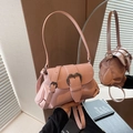 Pink saddle bag with glossy finish and silver heart buckle shown in hand - Pink