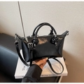 Detail einer schwarzen Lackleder-Handtasche mit geknoteten Griffen und silbernen Beschlägen - Schwarz