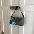 Dark grey textured shoulder bag with a bright blue elephant charm hanging on a white door - Black (With Charm)