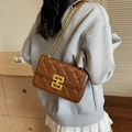 Brown quilted chain shoulder bag in glossy faux leather with gold hardware on female model - Coffee