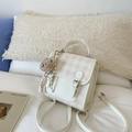 Detail shot of a beige plaid mini backpack featuring a silver buckle and cute bear pendant - With Charm / White