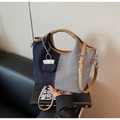 Détail du sac seau en denim bicolore avec bordure en cuir brun et mini breloque - Bleu