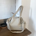 Beige große Canvas-Tragetasche mit breiten Gurten und Etikett auf dem Holztisch - Khaki
