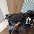 Close-up of black denim sling bag with metal zipper and wide adjustable strap details - Black