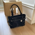 Detail of black glossy tote bag with metal buckle straps and silver heart pendant - Black