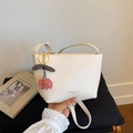Detail view of cream bucket bag with KOSK text and a red cherry charm accessory - White with Pendant