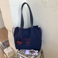 Dettaglio borsa tote in tela blu navy con ricamo rosso e chiusura con coulisse regolabile - Blu