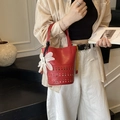Red hollow-out bucket bag featuring a white daisy charm and stylish yellow drawstring - Red