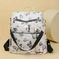 White butterfly print backpack with black straps and fringe charm accessory - Black