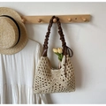 Détail d'un sac cabas en paille tissé à la main avec bandoulière en cuir marron en intérieur - Blanc Cassé