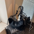 Glossy black hobo bag with silver bow accent and slim straps in minimalist setting - Black