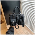 Close-up of black biker style handbag with silver rivets and dual buckled front pockets - Black
