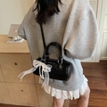 Chic black cylinder bucket bag with white lace bow and pearl charm shown on a table - Black with Pendant