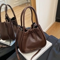 Dark brown pleated bucket bag with gold logo and dual handles for versatile styling - Brown
