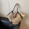 Summer straw tote bag with black leather trim and handles on a luxury sofa setting - Black